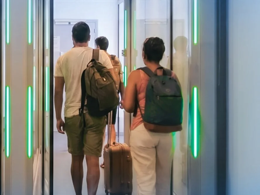 Voyageurs franchissant un SAS de sécurité anti-retour équipé de signalisation lumineuse à l'aéroport de Nouméa – La Tontouta